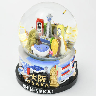 musubiオリジナルスノードーム  レトロな雰囲気がほんまもんの街「新世界」がテーマです。  通天閣を中心に串カツなど絶品グルメと幸運の神様ビリケンさんで浪速の下町文化を賑やかに表現しました。台座はアートな外観の飲食店と街を散策する観光客を造形しました。